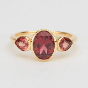Ring : Oval shaped garnet between two beautiful juicy orange pear shaped sapphires in 18K yellow gold.